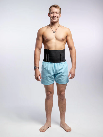 A man standing in a hernia support belt grey background 